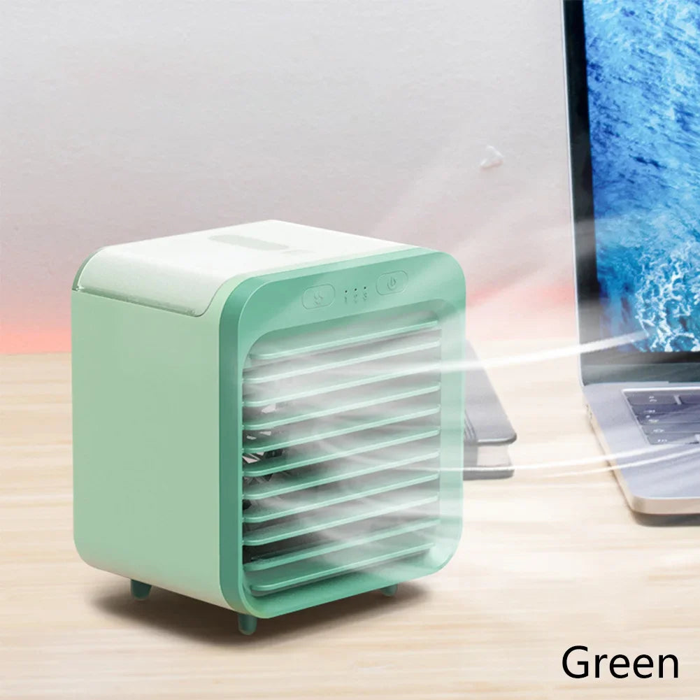 Green rechargeable mini air cooler and humidifier with mist, next to a laptop on a wooden desk.