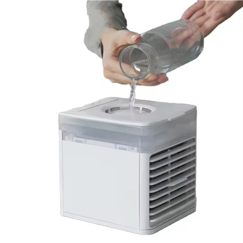 White mini water-cooled spray desk fan with a person pouring water into its top reservoir.
